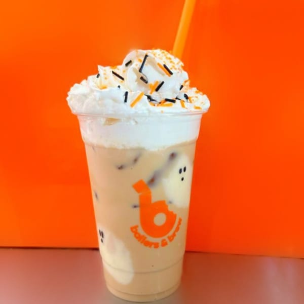 Iced coffee with whipped cream, orange and black sprinkles, and ghost-shaped marshmallows.